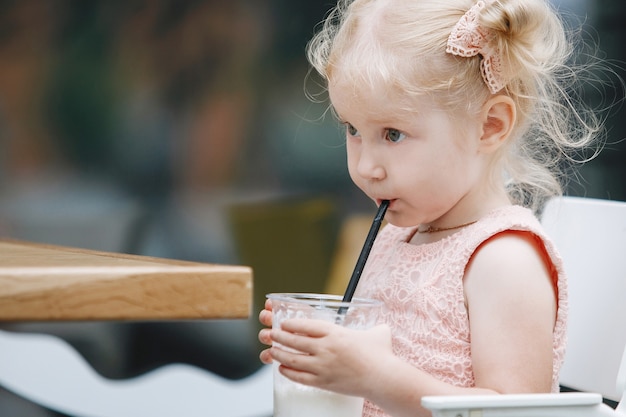 Blond en een milkshake aan een tafel in een stadsstraat