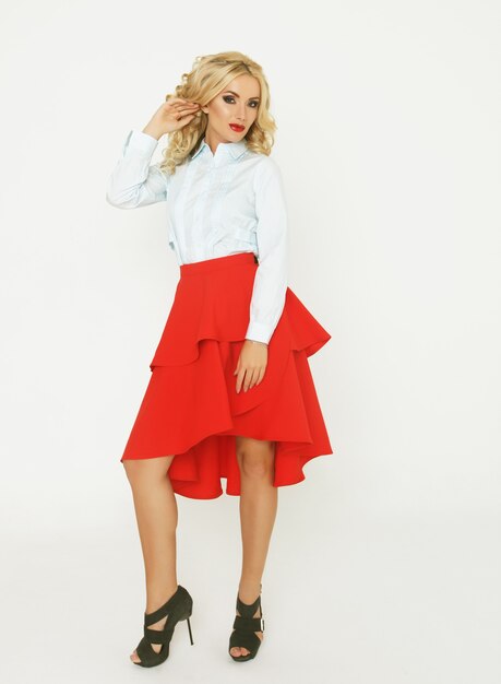 Blond fashion model with luxury  hair  and red skirt in studio over white  background