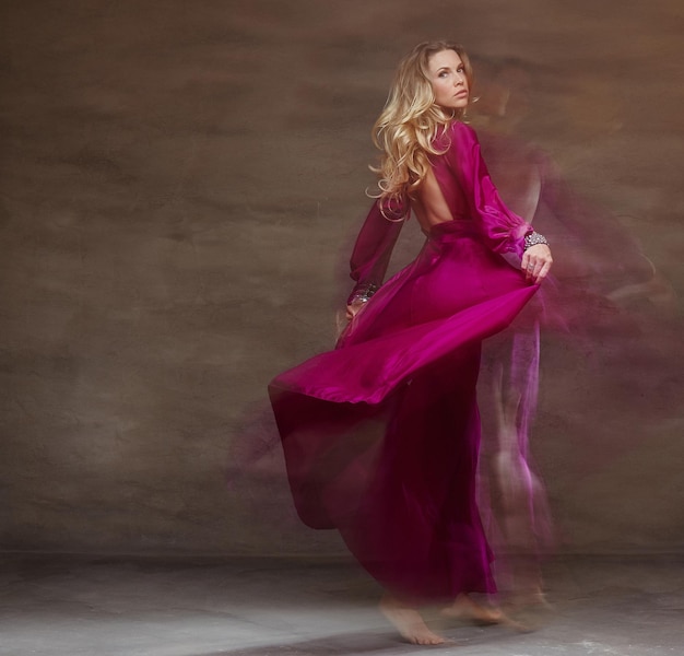 Blond female dancing  in long red dress