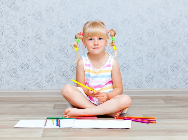 Blond gelukkig klein meisje trekt thuis op de vloer liggen. Vroegschoolse educatie