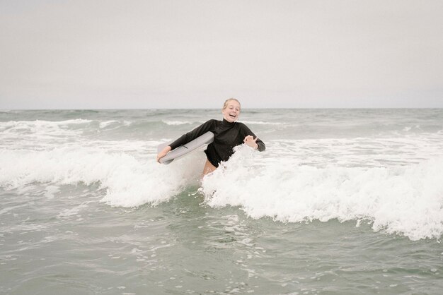 写真 海でボディーボードをするブロンドの女の子