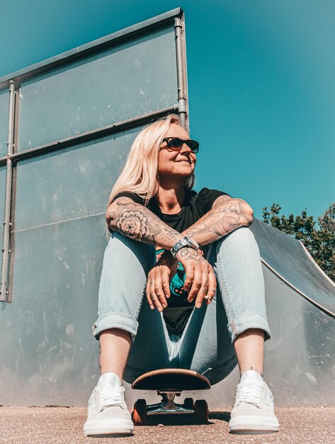 Photo blond girl sitting on her skateboard