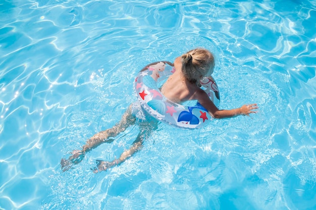 Blond girl swims with an inflatable ring in the pool Top view flat lay