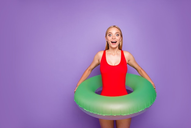 Foto ragazza bionda con galleggiante verde intorno alla vita isolata sulla porpora