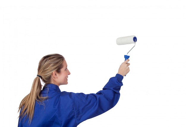 Blond girl with a roller painting a white wall