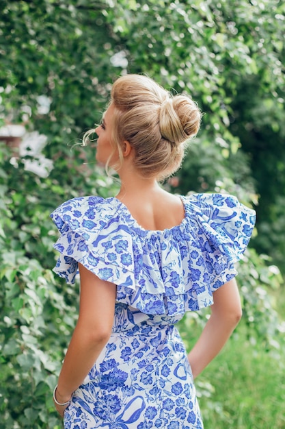 Blond haar vrouw terug met mode kapsel op zomertuin achtergrond