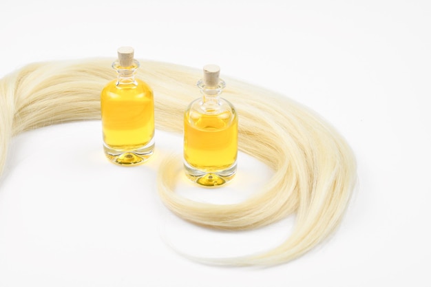 Capelli biondi e bottiglie di olio isolate su sfondo bianco