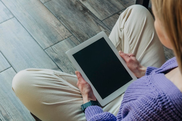 Blond hair woman sits on the floor with the tablet