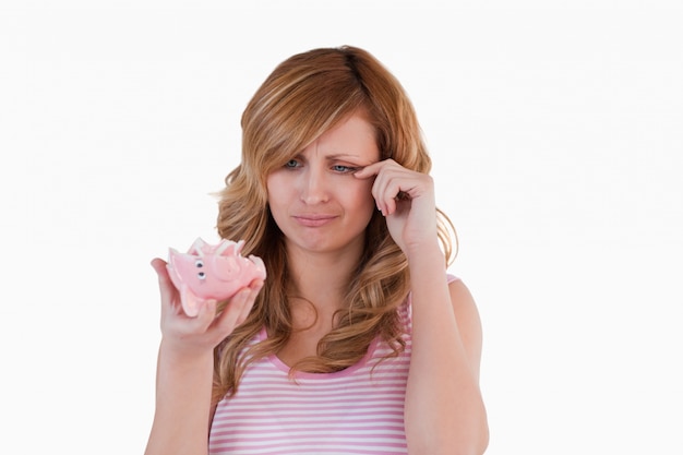 Blond-haired woman crying while holding her broken piggybank