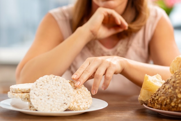 アレルギーのためにパンではなくポテトチップスを食べてテーブルに座っているブロンドの髪の女性