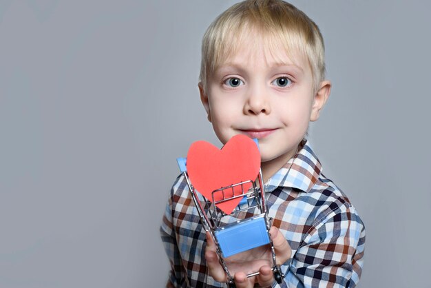 Blond jongetje met een metalen winkelwagentje met een hartvormige briefkaart erin