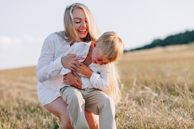 Blond jongetje spelen met moeder met wit haar met hooi in veld. zomer, zonnig weer, landbouw. gelukkige jeugd.