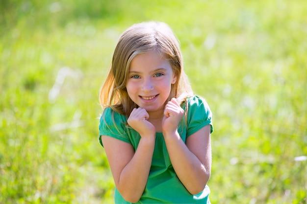 Blond kid girl excited gesture expression in green outdoor