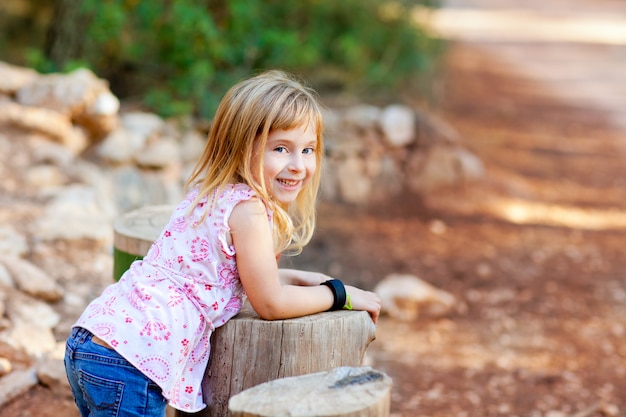 blond kid girl in tree trunk forest