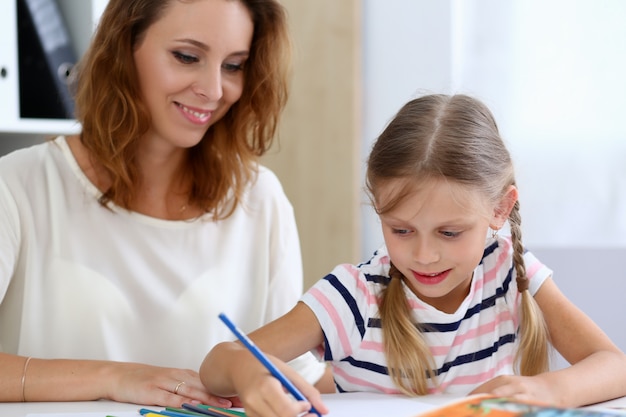 Blond little girl hold in arm pencil drawing something