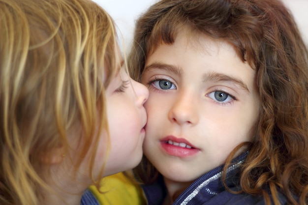 Blond little girl kissing her daughter blue eyes