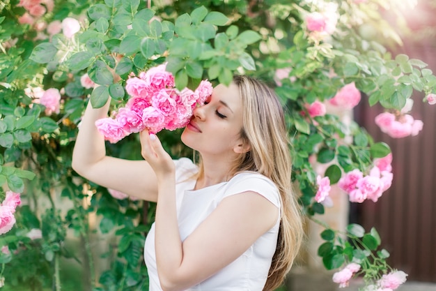 Blond lovely girl with blooming rosesOutdoors portraitspring time