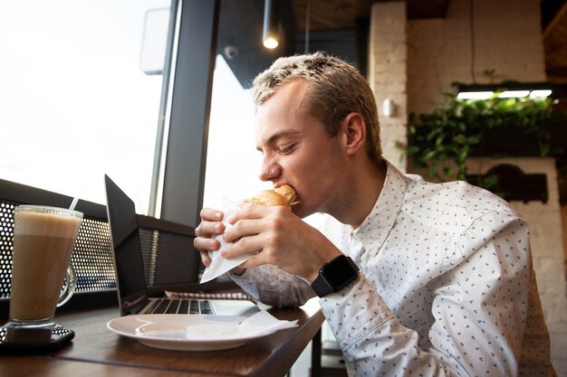 Blond man enjoying croissant in cafe