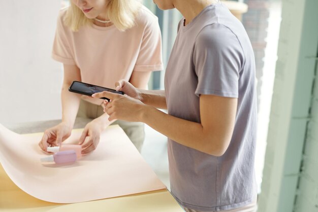 Blond meisje dat schoonheidsproducten op papier zet terwijl ze collega helpt