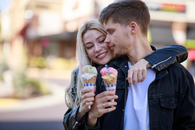 Blond meisje houdt ijs vast en knuffelt haar vriendje foto van hoge kwaliteit