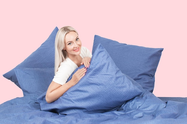 blond meisje in bed met witte kussens en een deken in een lichte slaapkamer, huishoudtextiel