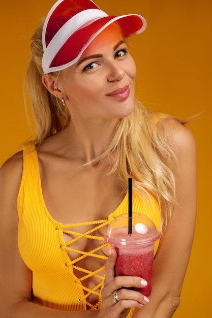 Blond meisje in een badpak en hoed met een cocktail