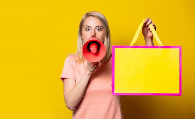 Foto blond meisje in roze jurk met boodschappentassen en megafoon