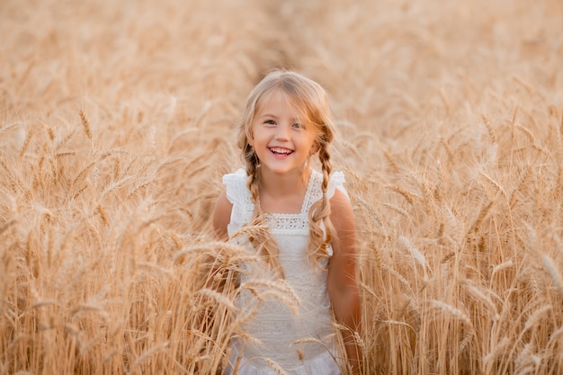 Blond meisje loopt in een zomer-tarweveld