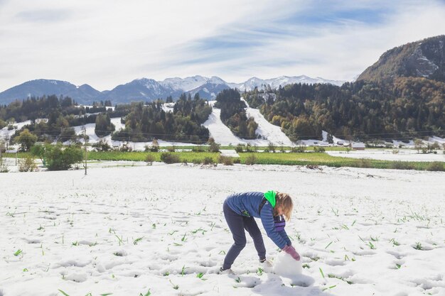 blond meisje maakt een sneeuwpop in Slovenië in de Alpen