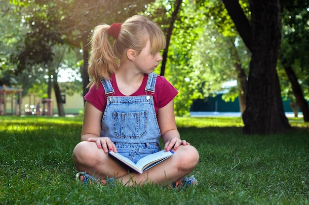 Blond meisje met boek op groen gras