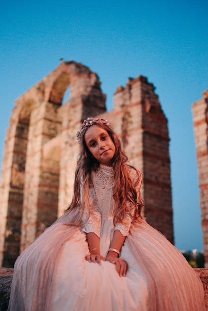 Blond meisje met krullend haar gekleed in communie jurk in Merida