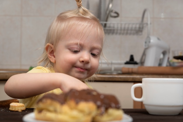 Blond meisje neemt koekjes in de keuken. kind en snoep.