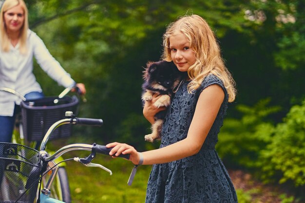 Blond meisje op een fiets houdt een Spitz-hond vast.