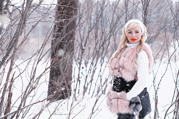 Blond meisje op een wandeling in een winterpark met een bewolkte dag