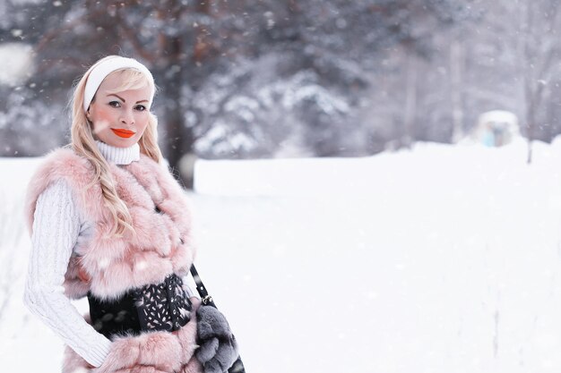 Blond meisje op een wandeling in een winterpark met een bewolkte dag