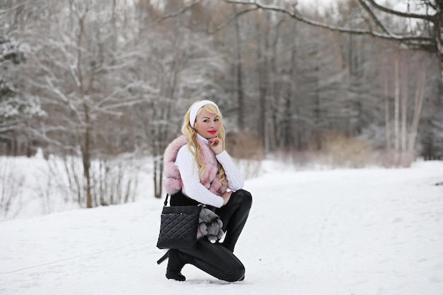 Blond meisje op een wandeling in een winterpark met een bewolkte dag