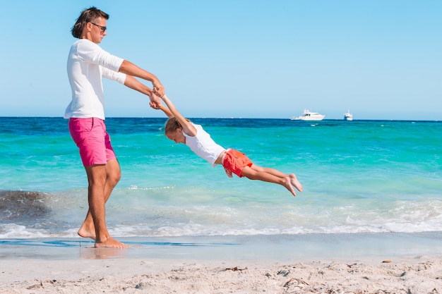 blond meisje speelt met zijn vader op het strand