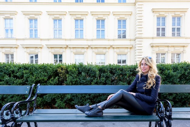Blond meisje, zittend op een bankje in Wenen