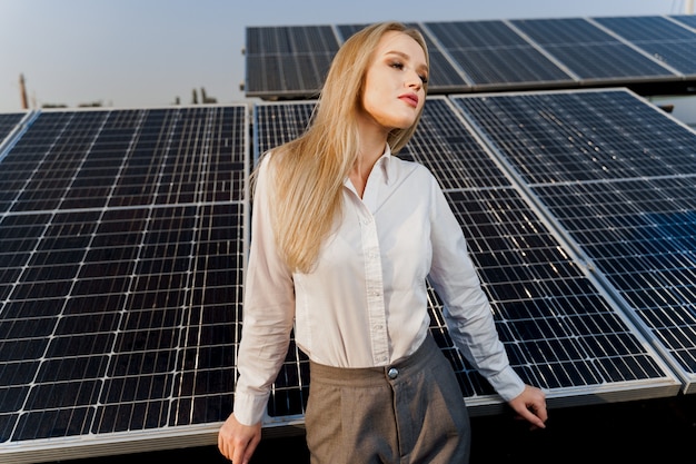 Blond model met zonnepanelen staat in rij op de grond