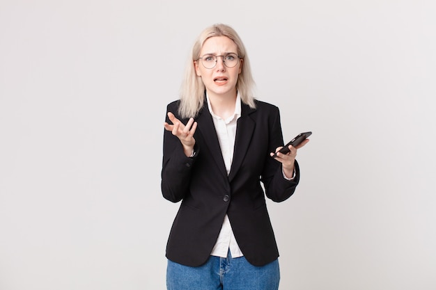 Blond pretty woman looking desperate, frustrated and stressed and holding a mobile telephone