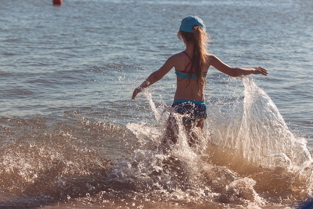 Blond schattig zevenjarig meisje dat plezier heeft en plezier heeft aan zee tijdens de vakantie.