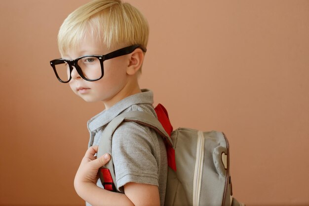 a blond schoolboy in glasses and with a backpack