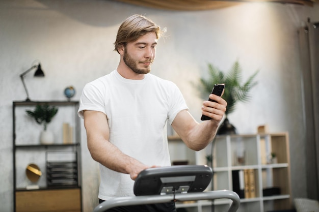 Blond sportsman having workout on treadmill indoors his home