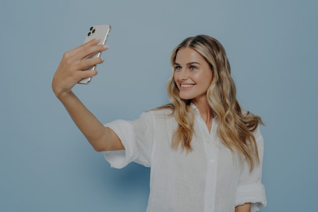 Blond tienermeisje dat selfie maakt terwijl ze lacht