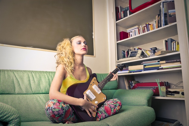 Blond tienermeisje met een paarse gitaar