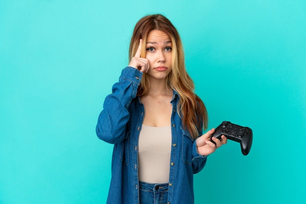 Blond tienermeisje speelt met een videogamecontroller over een geïsoleerde muur en denkt aan een idee