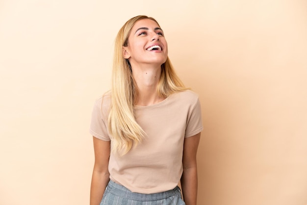 Blond Uruguayaans meisje geïsoleerd op beige achtergrond lachen