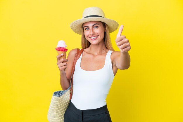 Blond Uruguayaans meisje in de zomer met ijs geïsoleerd op een gele achtergrond met duimen omhoog omdat er iets goeds is gebeurd