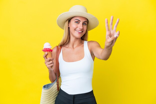 Blond uruguayaans meisje in de zomer met ijs geïsoleerd op gele achtergrond gelukkig en drie tellen met vingers