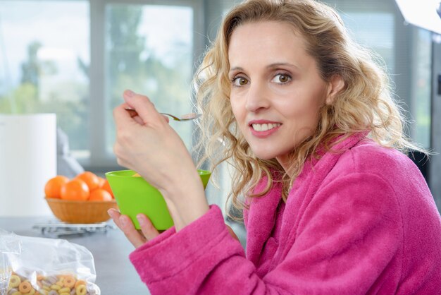 Blond woman eating cereals, at morning